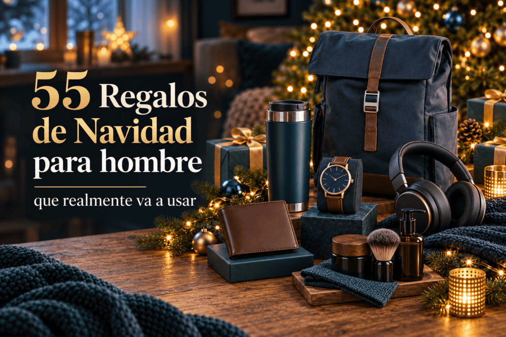 Imagen destacada de "55 Regalos de Navidad para hombre que realmente va a usar", con una mochila azul con detalles de cuero, un termo verde, un reloj con correa marrón, unos audífonos negros, una cartera de cuero, un set de afeitado con brocha y frascos, y una bufanda azul oscuro sobre una mesa de madera junto a un árbol de Navidad decorado y regalos envueltos.